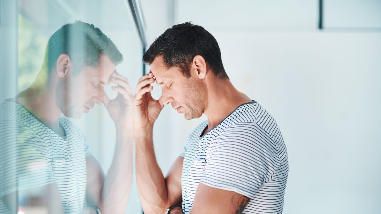 Man leaning against window feeling sad