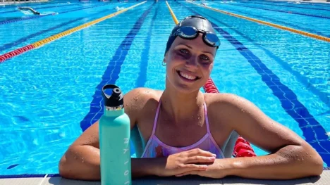 Moesha Johnson smiling and leaning of the edge of a competition swimming pool.